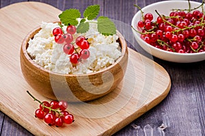 Cottage cheese with red berries and mint in a wooden bowl/cottage cheese with red berries and mint in a wooden bowl. selective