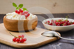 cottage cheese with red currant in a wooden plate/cottage cheese with red currant in a wooden plate on a dark backgraund.