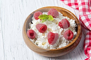 Cottage cheese with ripe raspberries and green mint leaves, fresh berries, healthy breakfast concept