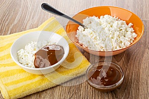 Cottage cheese, spoon, bowl with cottage cheese and boiled condensed milk on napkin on table