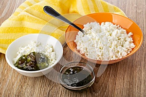 Cottage cheese, spoon, bowl with cottage cheese and gooseberry jam, napkin on table