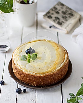 Cottage cheese tart with poppy seeds and blueberries on a light table. Bright spring photo with flowers.