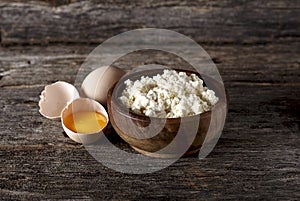 Cottage cheese in a wooden bowl, eggs in rustic style. Dairy pro