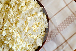 Cottage cheese in the wooden bowl on the napkin, top view