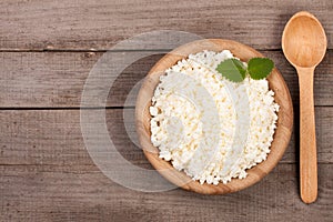 Cottage cheese in a wooden bowl on old wooden background with copy space for your text. Top view
