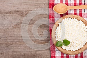 Cottage cheese in a wooden bowl on old wooden background with copy space for your text. Top view