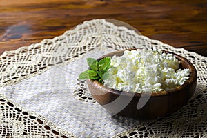Cottage cheese in a wooden bowl on old wooden background with copy space for your text. Top view