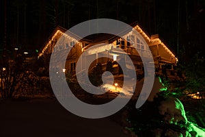 The cottage is decorated for Christmas. Winter landscape with a house. The house is decorated with festive illumination