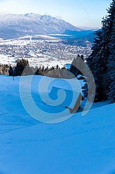 Cottage in snow covered mountain side with view over Garmisch Partenkirchen