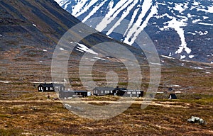 Cottage under a big, partially snowy mountain