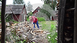 Cottager split hard log in country woodshed in summertime. 4K