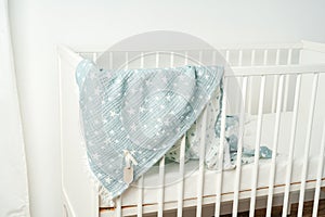 Cotton baby blanket with paper tag hanging from baby bed