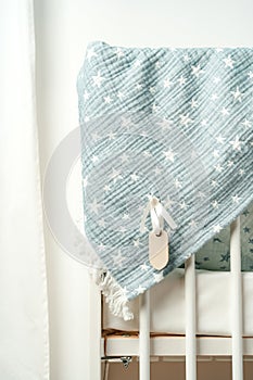 Cotton baby blanket with paper tag hanging from baby bed