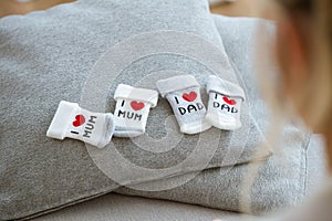 Cotton baby socks for newborn on a grey pillow while future mother looking they at home