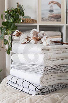 Cotton branch with pile of folded bed sheets and blankets