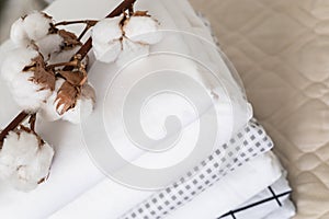 Cotton branch with pile of folded bed sheets and blankets