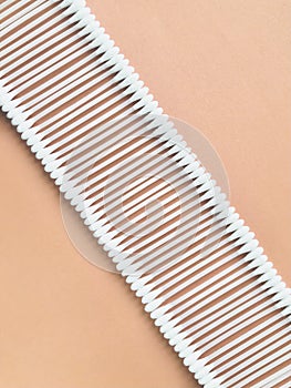 Cotton buds arranged diagonals in a row on a beige background.