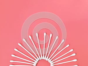 Cotton buds arranged in a semicircle on a pink background.
