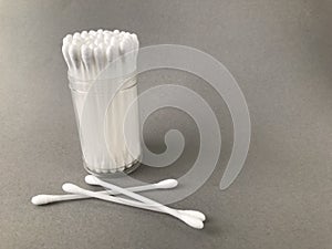 Cotton buds in a container on a grey background.