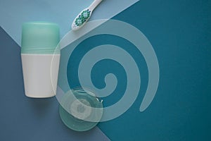 Cotton buds for ears and pads for face on blue background. A deodorant with cover of turquoise color, toothbrush and dental floss