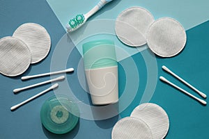 Cotton buds and pads on blue background. A deodorant with cover of turquoise color, toothbrush and dental floss.