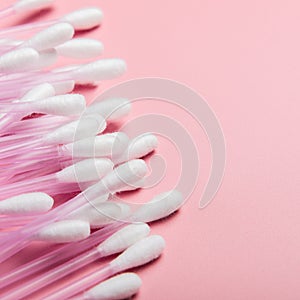 Cotton buds on a pink background. Hygienic supplies, a tool for beauty. Top view, copy space