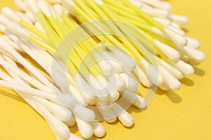 Cotton made ear buds all together close display on yellow background.