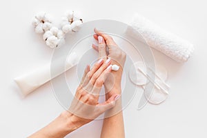 Cotton pads, swabs, cream, hands on white background top view