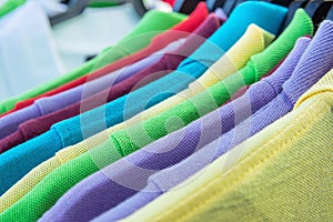 Cotton Polo Shirts of Various Colors Blue Yellow Red Purple Green White Hanging on Hangers on Rack in Clothing Store. Sales Retail