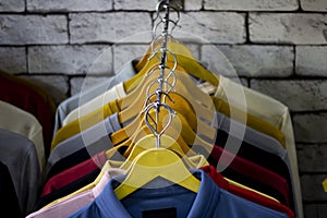 Cotton and sports t-shirts hung on wall hanger racks inside a clothes shop low angle view with the focused depth of field