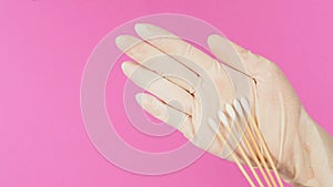 Cotton sticks for swab test in hand palm with white medical gloves or latex glove on pink background