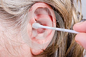 Cotton swab against the human ear close-up