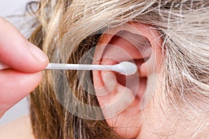 Cotton swab near human ear before ear cleaning close-up