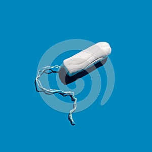 Cotton tampon on a blue solid background. Feminine hygiene care.