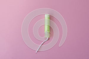 Cotton tampon with light green applicartor on a pink background. Woman days hygiene protection. Menstrual cycle period concept.