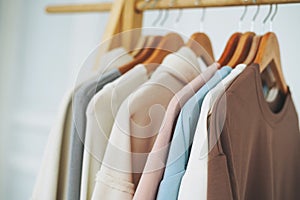 Cotton tops sweatshirts in natural tones on wooden shelf in bright room