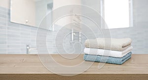 Cotton towels on wooden table in blurred bathroom interior background