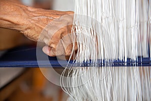 Cotton weaving. Close-up woman hand weaving cotton on manual loom. Thai cotton handmade. Homespun fabric process. The process of