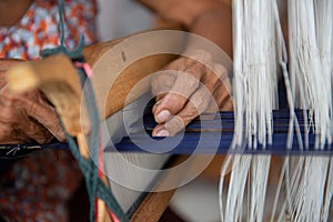 Cotton weaving. Close-up woman hand weaving cotton on manual loom. Thai cotton handmade. Homespun fabric process. The process of