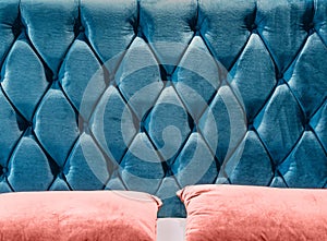 Couch-type velours screed on headboard tightened with buttons. Blue chesterfield style quilted upholstery backdrop close