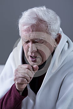 Coughing man covered with blanket