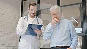 Coughing Old Man Discussing Health issues with Doctor
