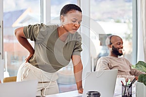 Could it be my chair or something else.... Shot of a businesswoman experiencing back pain while getting up from her desk