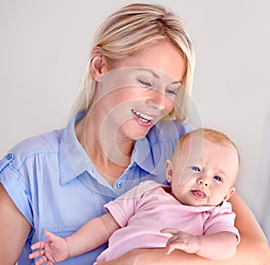 She could spend all day just holding her little girl. Young mother laughing and holding her cute baby.