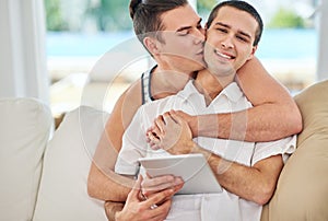 We couldnt be any more in love. Portrait of an affectionate gay couple using a digital tablet while relaxing on the sofa