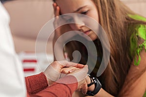 Counseling professional trying to provide comfort to sad teenager girl holding her hands - close up