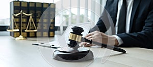 Counselor lawyer or notary working on a documents and report of the important case and wooden gavel, brass scale on table in