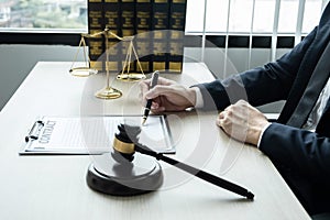 Counselor lawyer or notary working on a documents and report of the important case and wooden gavel, brass scale on table in