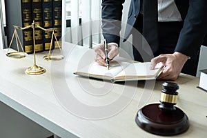 Counselor lawyer or notary working on a documents and report of the important case and wooden gavel, brass scale on table in