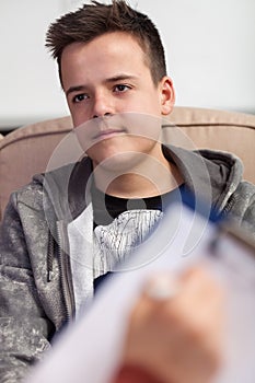 Counselor, psychiatrist or doctor taking notes on teenager young boy